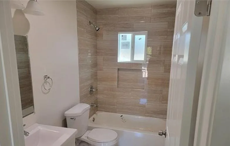 Baño con azulejo alrededor de la tina y un nicho empotrado