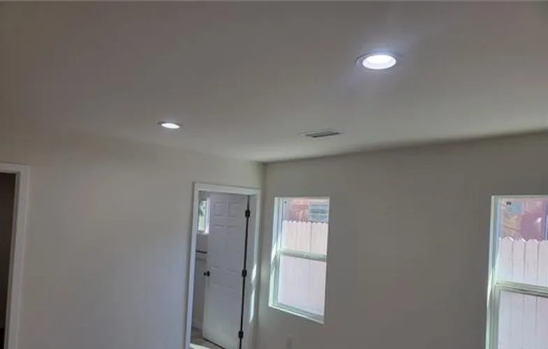 Cuarto vacío con luces empotradas, piso tipo madera y dos ventanas
