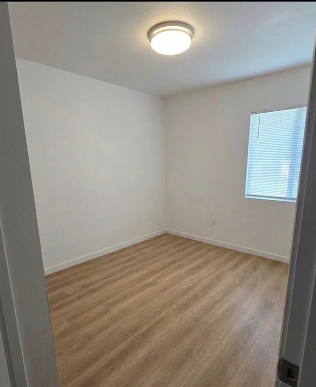Recámara vacía con una ventana y piso tipo madera