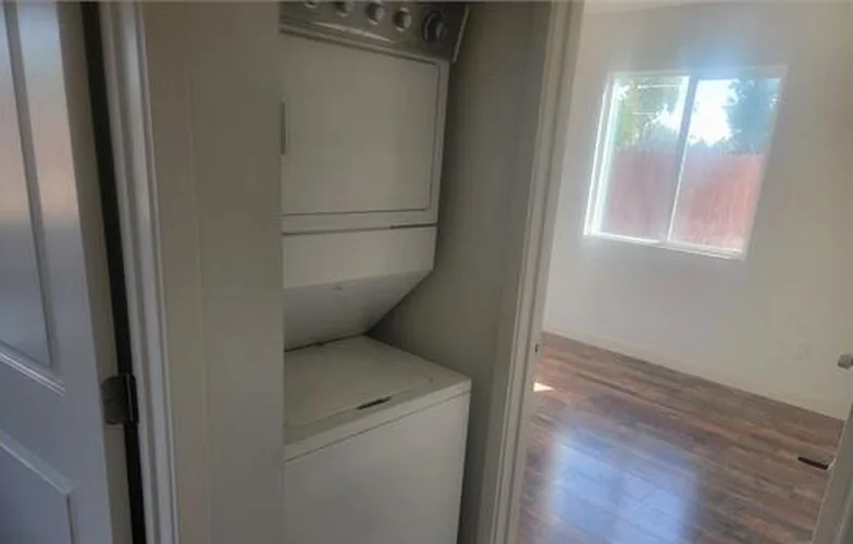 Clóset de lavandería con lavadora y secadora apiladas junto a una recámara