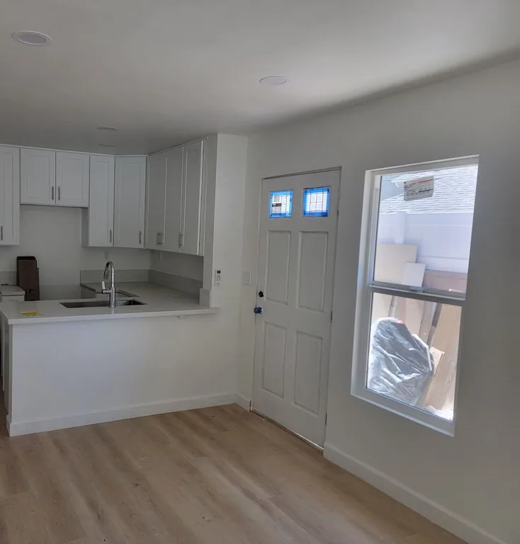 Cocina con gabinetes blancos y una península junto a una puerta exterior