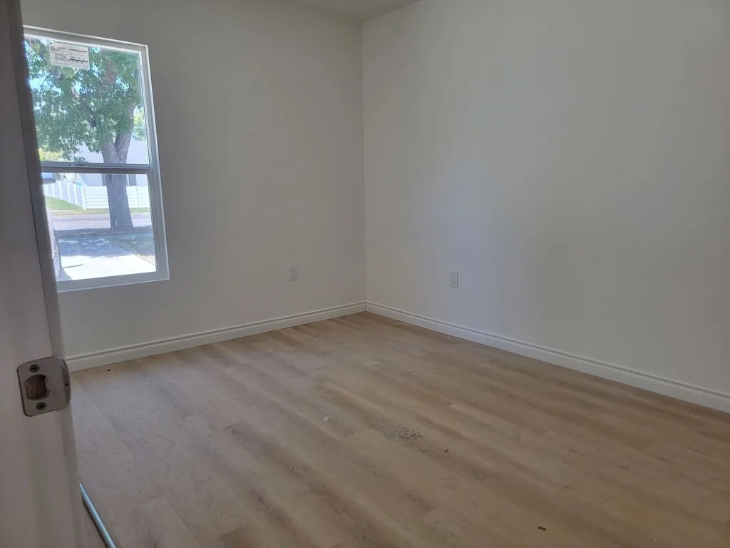 Recámara vacía con piso tipo madera y una ventana